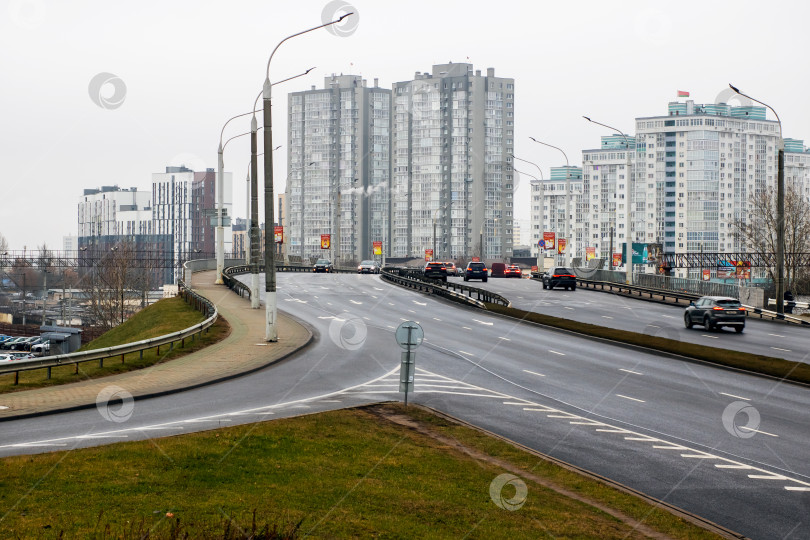 Скачать Беларусь, Минск - 02.01.2025: Автомобили едут по оживленному шоссе на фоне городских зданий фотосток Ozero