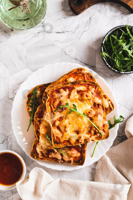 Скачать Хрустящая пицца с беконом, сыром и кетчупом на тостах, выложенная на тарелку сверху и в вертикальном положении фотосток Ozero