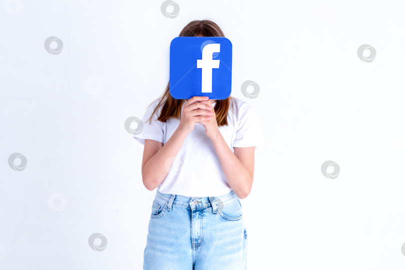 Скачать Белый подросток держит в руках фотографию с логотипом Facebook на белом фоне. Турция, Стамбул, 29 мая 2022 г. фотосток Ozero