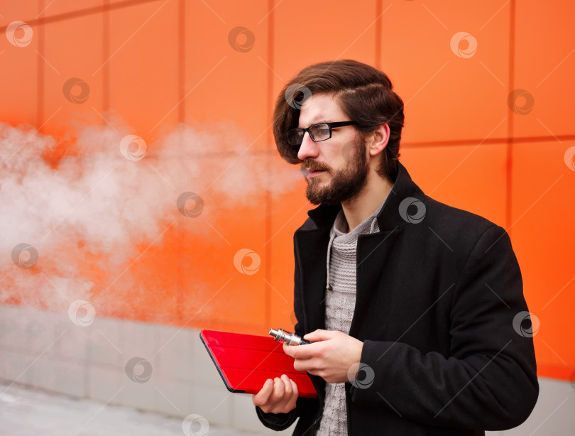 Скачать Мужчина с электронной сигаретой и планшетным ПК. фотосток Ozero