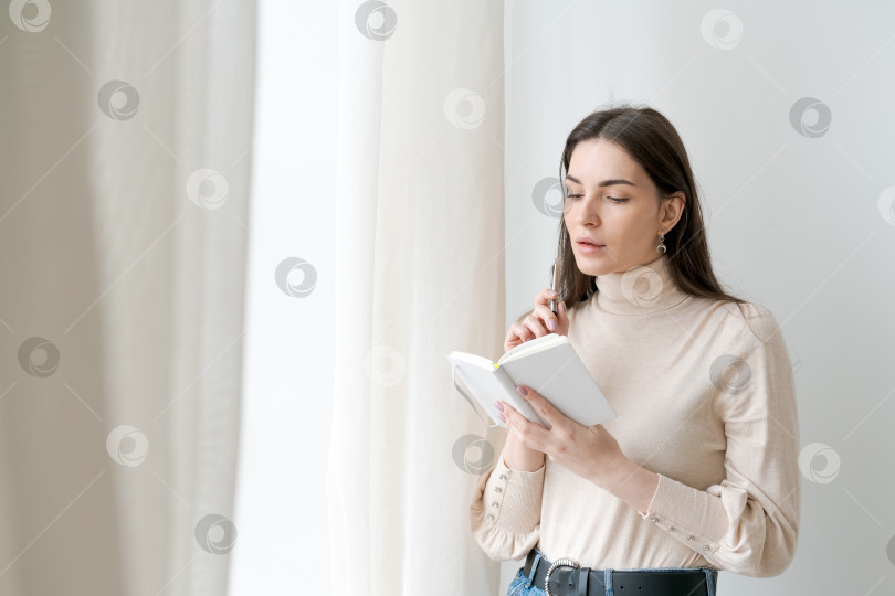 Скачать Женщина сидит перед окном и читает книгу фотосток Ozero