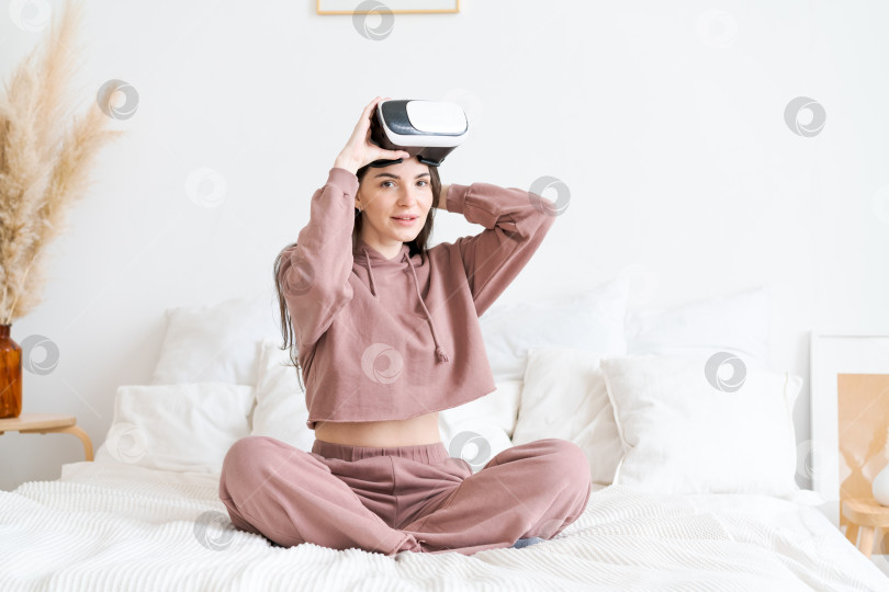 Скачать Женщина сидит на кровати в розовой толстовке с капюшоном фотосток Ozero
