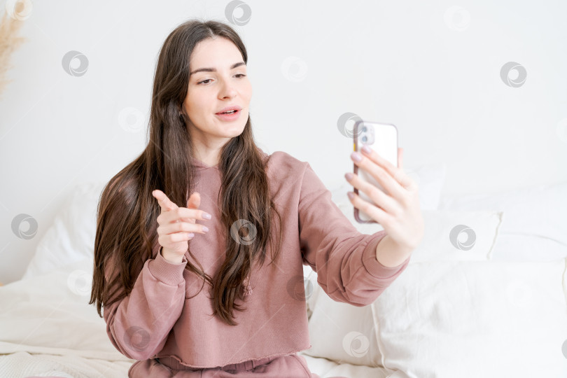 Скачать Женщина сидит на кровати и фотографирует себя на мобильный телефон фотосток Ozero
