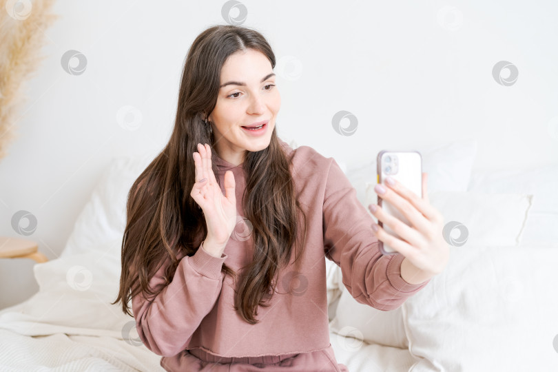 Скачать Женщина сидит на кровати и фотографирует себя на мобильный телефон фотосток Ozero