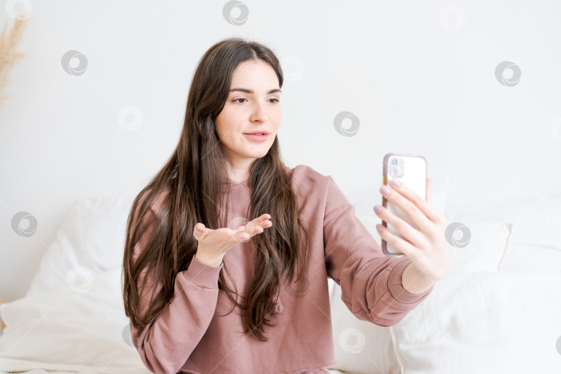 Скачать Женщина сидит на кровати и фотографирует себя на мобильный телефон фотосток Ozero