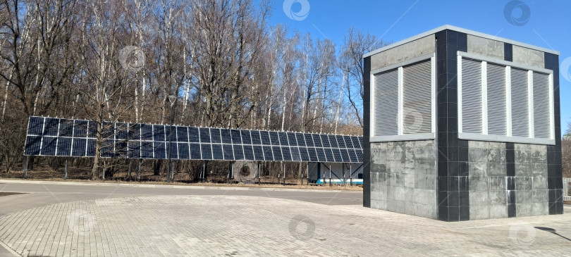 Скачать Солнечные панели расположены рядом с современным зданием в лесистой местности. Установка эффективно улавливает солнечный свет, сливаясь с природой фотосток Ozero