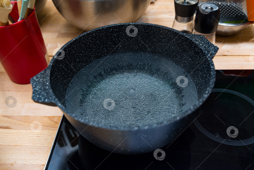 Скачать Черная кастрюля с кипящей водой на плите. фотосток Ozero