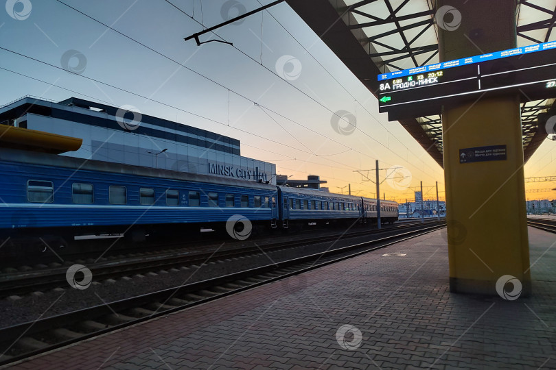 Скачать Беларусь, Минск - 27.03.2025: Бело-голубой поезд в настоящее время стоит на оживленной железнодорожной станции фотосток Ozero