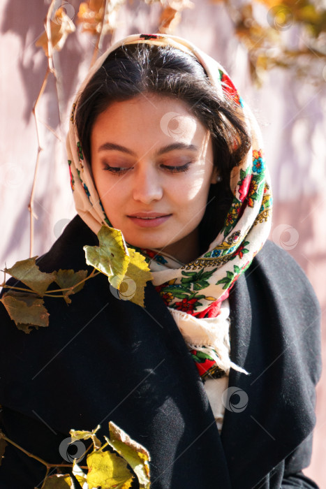 Скачать Красивая девушка сидит в парке на качелях, на голове у нее традиционный русский платок фотосток Ozero