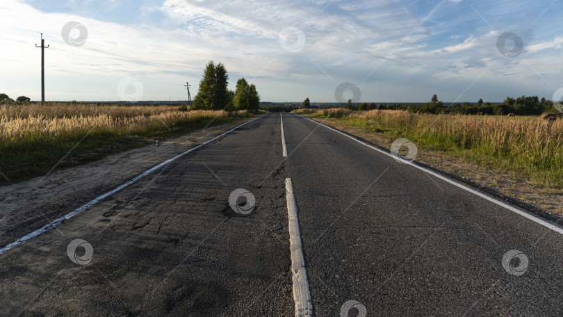 Скачать Асфальтированная дорога в сельской местности, обозначенная на дороге. По краям деревьев и обочинам дорог фотосток Ozero