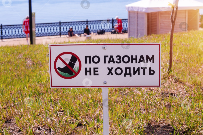 Скачать Табличка По газонам не ходить с изображением ноги в красном перечеркнутом круге на фоне набережной и отдыхающих спортсменов фотосток Ozero