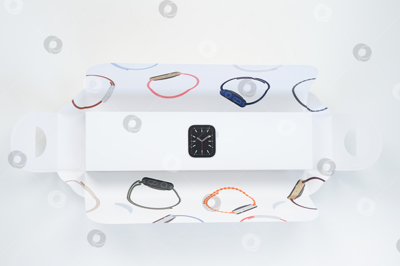 Скачать Распаковка новых Apple Watch Series 6 с серебристым алюминиевым корпусом диаметром 40 мм и белым спортивным ремешком на белом фоне. Шаг четвертый. Россия, Татарстан, 10 июня 2021 года фотосток Ozero