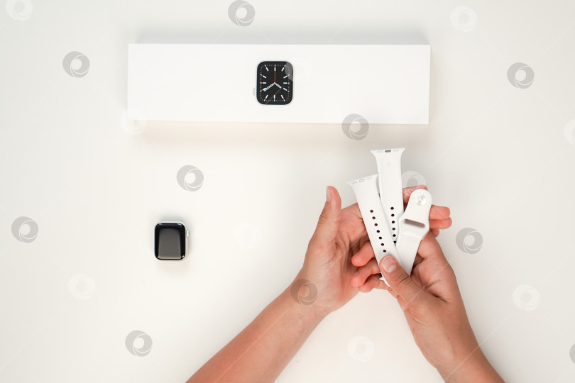 Скачать Распаковка новых Apple Watch Series 6 с серебристым алюминиевым корпусом диаметром 40 мм и белым спортивным ремешком на белом фоне. Шаг шестой. Россия, Татарстан, 10 июня 2021 года фотосток Ozero