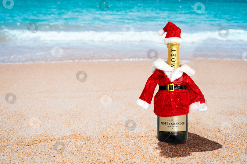 Скачать Бутылка шампанского Moet Chandon в костюме Санта-Клауса на берегу моря. Новогодняя и рождественская концепция. Россия, Татарстан, 12 октября 2019 года. фотосток Ozero
