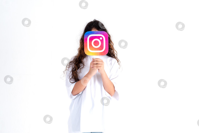 Скачать Подросток белой расы держит в руках фотографию с логотипом Instagram на белом фоне. Подростки увлекаются новыми технологическими тенденциями - концепцией молодежи, технологий, общения и дружбы. Турция, Стамбул, 29 мая 2022 года фотосток Ozero
