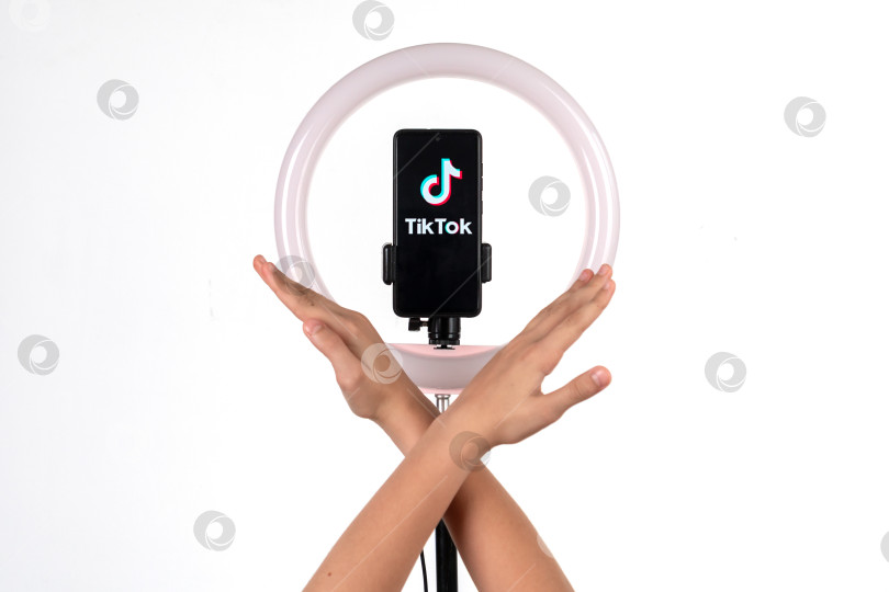 Скачать Логотип tiktok на смартфоне, прикрепленном к круглой лампе на штативе, и детские ручки символизируют запрет. Дональд Трамп предлагает запретить Tiktok в США. Россия, Казань - 08 августа 2020 г. фотосток Ozero