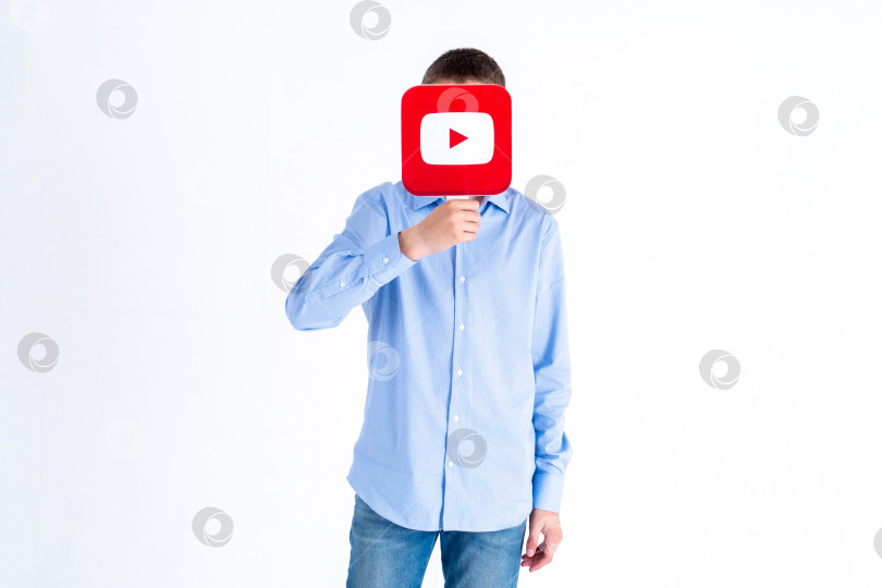 Скачать Юноша-европеец держит в руках картинку с логотипом Youtube на белом фоне. Подростки увлекаются новыми технологическими тенденциями - концепцией молодежи, технологий, общения и дружбы. Турция, Стамбул, 29 мая 2022 года. фотосток Ozero