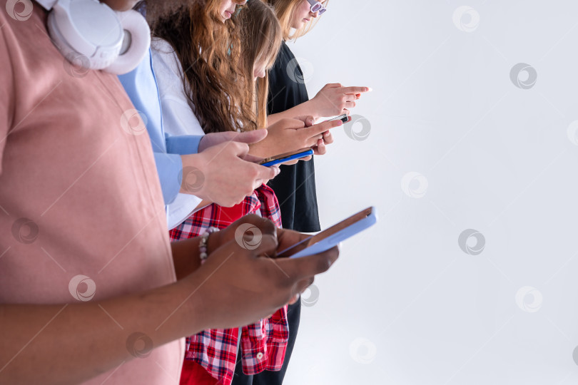 Скачать Группа друзей смотрит на смартфоны - Подростки, увлеченные новыми технологическими тенденциями - Концепция молодежи, технологий, общения и дружбы - Сосредоточьтесь на центре внимания фотосток Ozero