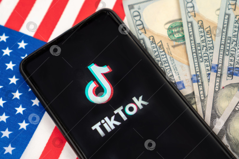 Скачать Логотип Tiktok на смартфоне и доллары США. Концепция запрета Tik tok, предложенная Дональдом Трампом. Россия, Казань - 08 августа 2020 г. фотосток Ozero