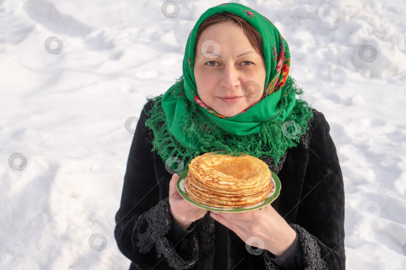 Скачать Русская женщина с блинами в руках на фоне белого снега. Масленица фотосток Ozero