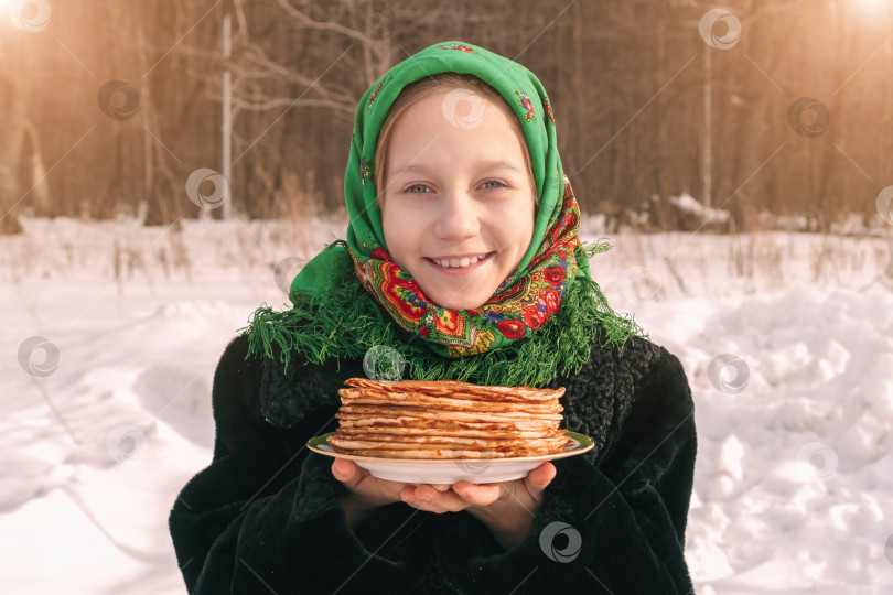 Скачать Очаровательная девушка в русском народном костюме сидит на снегу. . Концепция празднования русского масленичного праздника. фотосток Ozero