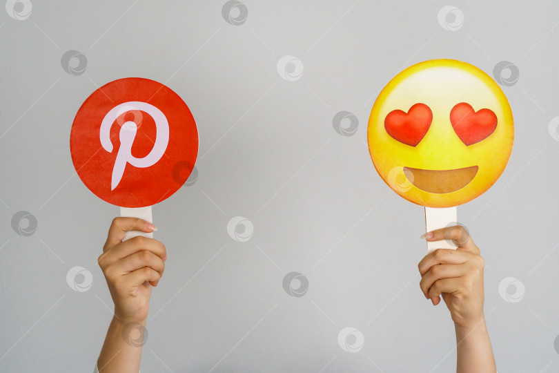 Скачать Девушка держит в руках значок с логотипом Pinterest и эмодзи с улыбкой и сердечками. Pinterest - самая любимая и лучшая концепция социальной сети. Турция, Стамбул, 17 сентября 2024 года. фотосток Ozero