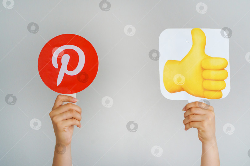 Скачать Девушка держит в руках значок с логотипом Pinterest и эмодзи "большой палец вверх". Pinterest - самая любимая и лучшая концепция социальной сети. Турция, Стамбул, 17 сентября 2024 года. фотосток Ozero