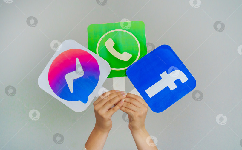 Скачать Девочка-подросток держит в руках логотипы Facebook messenger, WhatsApp и Facebook на сером фоне. Представление о подростках, пользующихся самыми популярными социальными сетями. Турция, Стамбул, 17 сентября 2024 года. фотосток Ozero