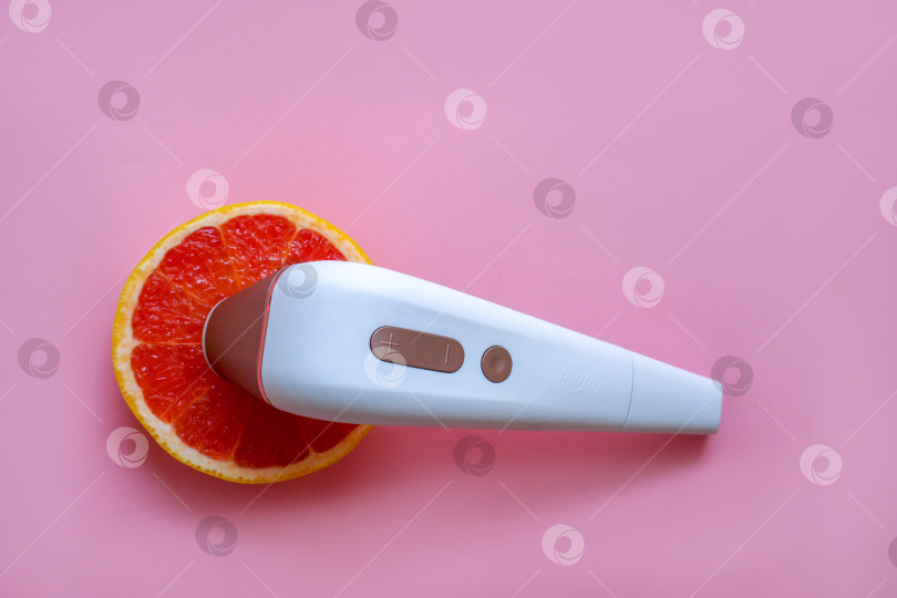 Скачать Бесконтактный стимулятор клитора Satisfyer и спелый грейпфрут на розовом фоне. Вибратор и мастурбация. Россия, Татарстан, 02 марта 2020 г. фотосток Ozero