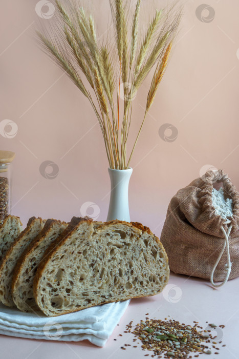 Скачать Хлеб ручной работы с вырезанными семечками, пакетик муки и пшеничная каша на бежевом фоне. фотосток Ozero