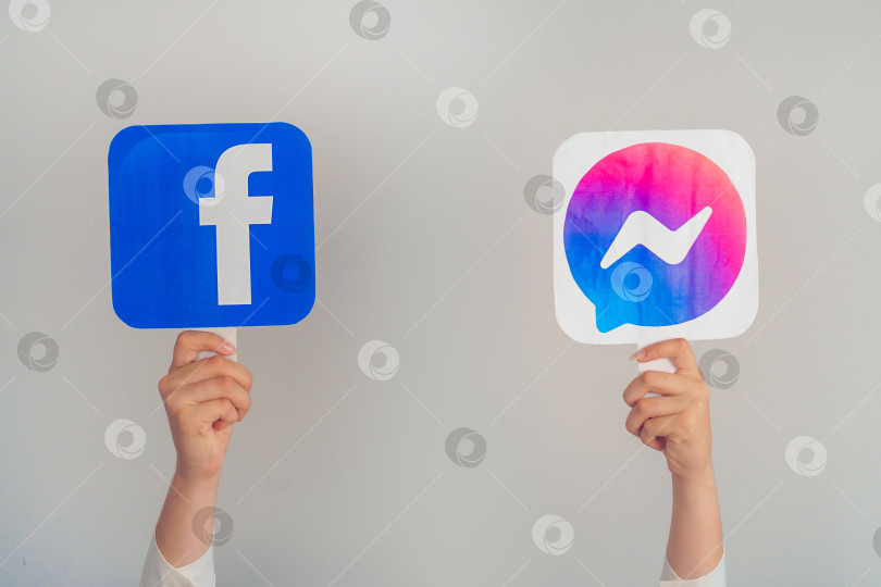 Скачать Девочки-подростки держат в руках логотипы Facebook и Facebook messenger на сером фоне. концепция молодежи, технологий, общения и дружбы. Турция, Стамбул, 17 сентября 2024 года. фотосток Ozero