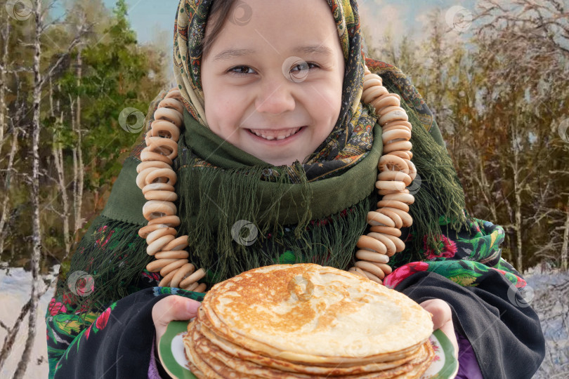 Скачать Очаровательная девушка в русском народном костюме сидит на снегу. Бусы из сушащихся рогаликов ,. Концепция празднования русского масленичного праздника. фотосток Ozero