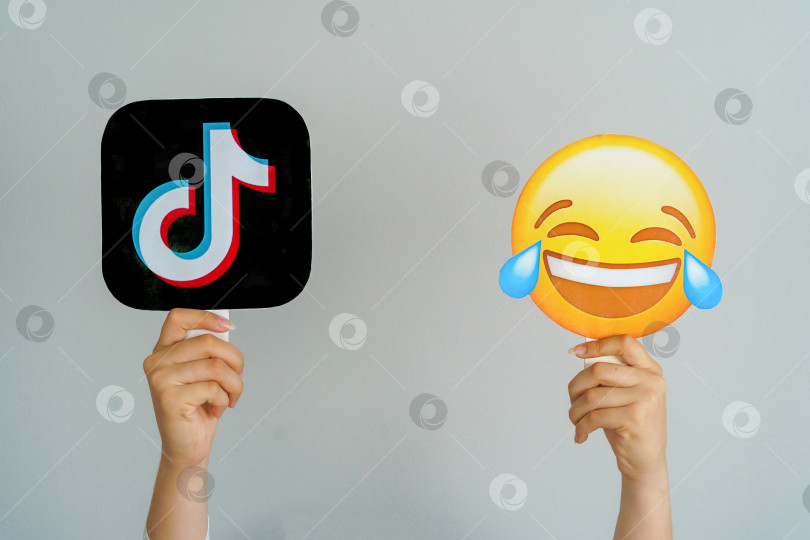 Скачать Девушка держит в руках значок с логотипом TikTok и смеющимся эмодзи. TikTok - самая любимая и лучшая концепция социальной сети. Турция, Стамбул, 17 сентября 2024 года. фотосток Ozero