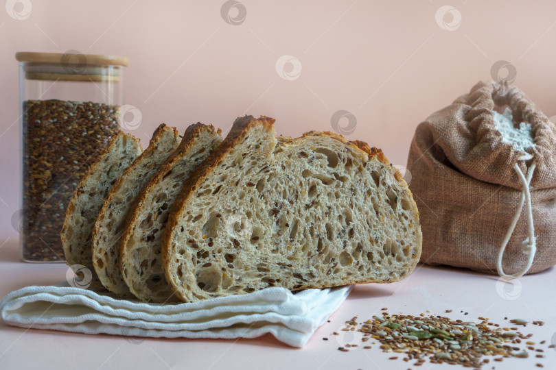 Скачать Хлеб ручной работы с вырезанными семечками, пакетик муки и пшеничная каша на бежевом фоне. фотосток Ozero