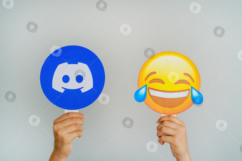 Скачать Девушка держит значок с логотипом Discord и смеющимися эмодзи. Discord - самая любимая и лучшая концепция социальной сети. Турция, Стамбул, 17 сентября 2024 года. фотосток Ozero
