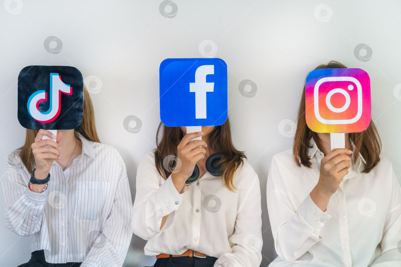 Скачать группа подростков с логотипами Facebook, Instagram, TikTok на сером фоне. Концепция использования подростками самых популярных социальных сетей. Турция, Стамбул, 17 сентября 2024 года. фотосток Ozero