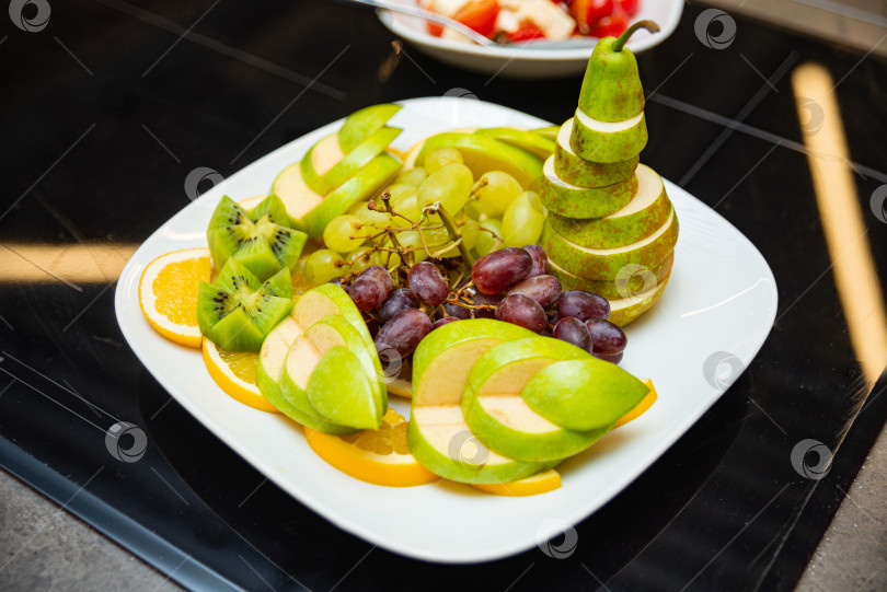 Скачать Яркое блюдо из свежих фруктов с нарезанными грушами и киви. фотосток Ozero