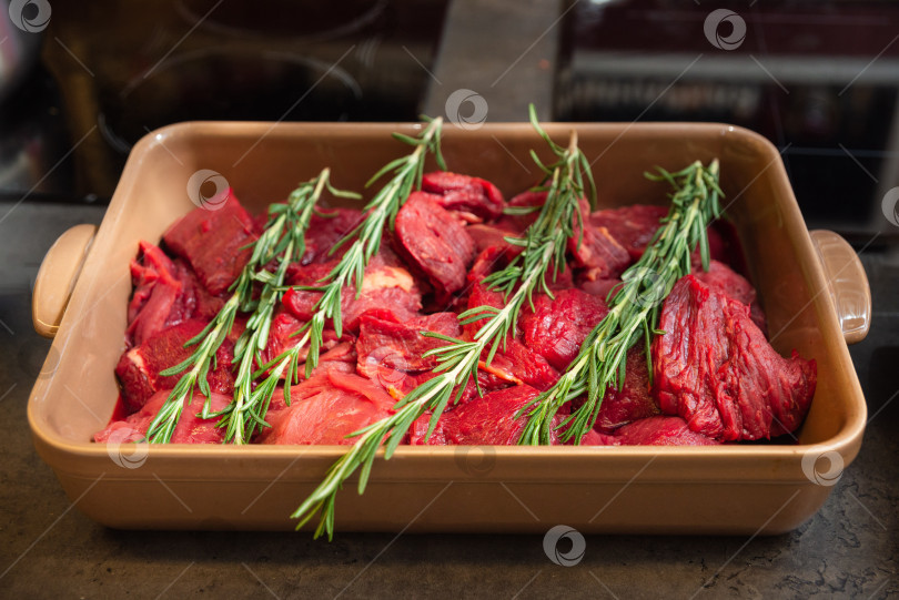 Скачать Куски сырой говядины с розмарином выложить в форму для запекания. фотосток Ozero