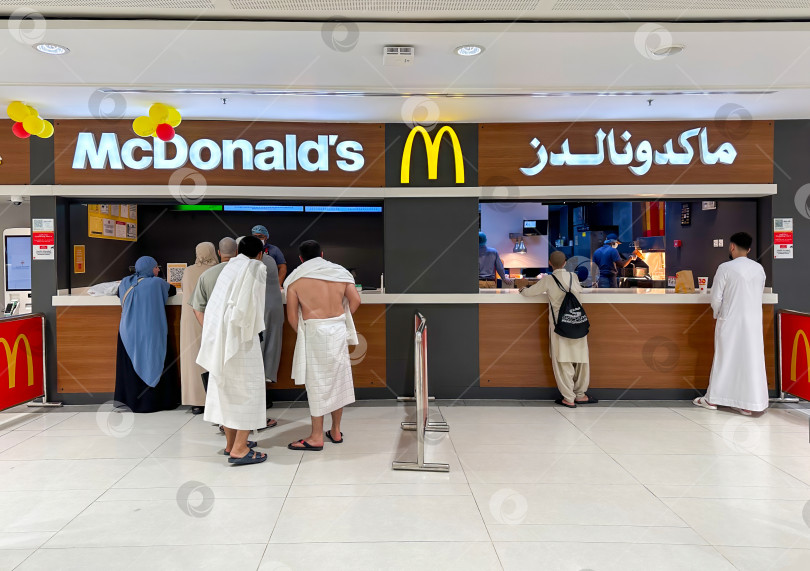 Скачать Посетители ресторана McDonald's, занятые оформлением заказов, стоят в очереди, Саудовская Аравия, Мекка, 24 ноября 2024 года фотосток Ozero