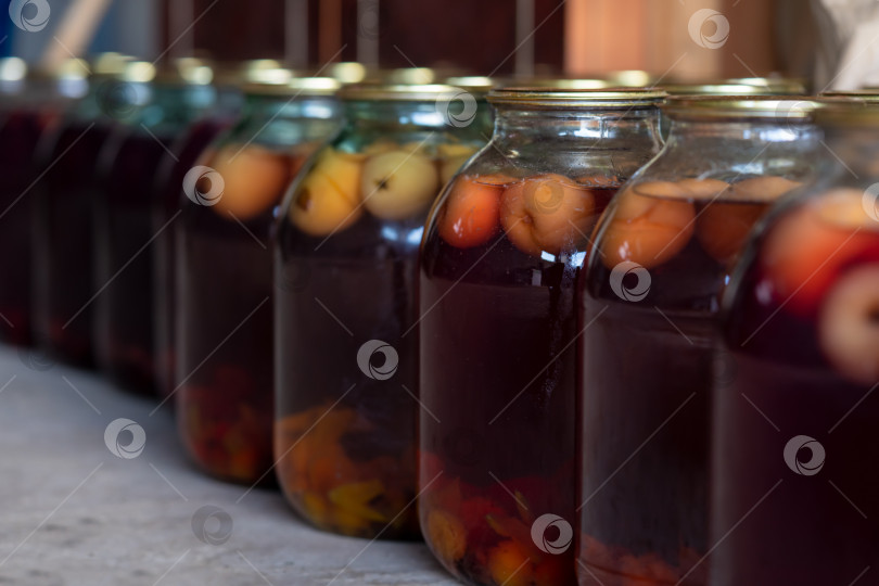 Скачать Стеклянные банки с яблочным компотом. Хранение напитков. Размытый фон. Вид сбоку. фотосток Ozero