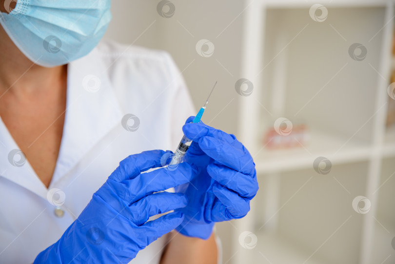 Скачать Женщина-врач держит в руках шприц с вакциной, готовясь сделать инъекцию. Концепция клинических испытаний коронавирусной инфекции, вакцинация фотосток Ozero