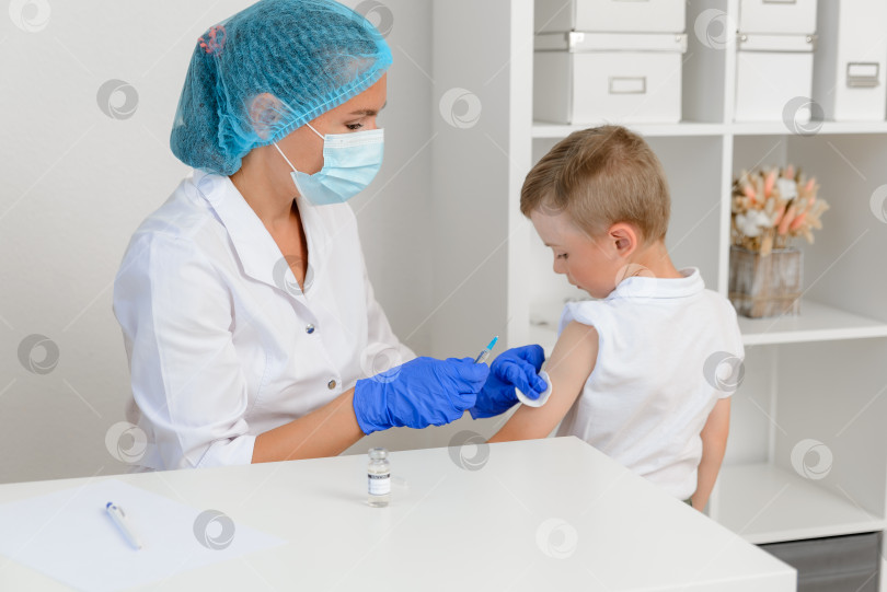 Скачать Концепция детской вакцинации в борьбе с коронавирусом. Врач делает укол маленькому мальчику фотосток Ozero