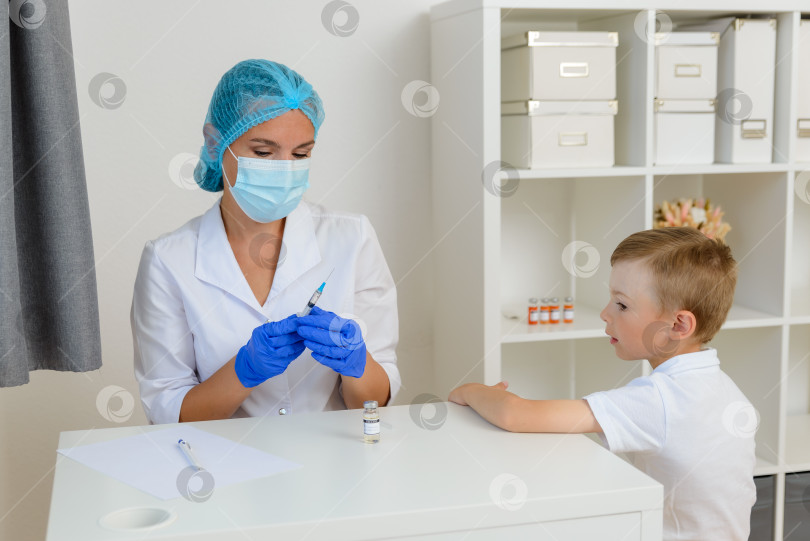 Скачать Женщина-врач держит в руках шприц с вакциной от covid-19. Готовится к вакцинации ребенка. Концепция прививок для детей в борьбе с коронавирусом. фотосток Ozero