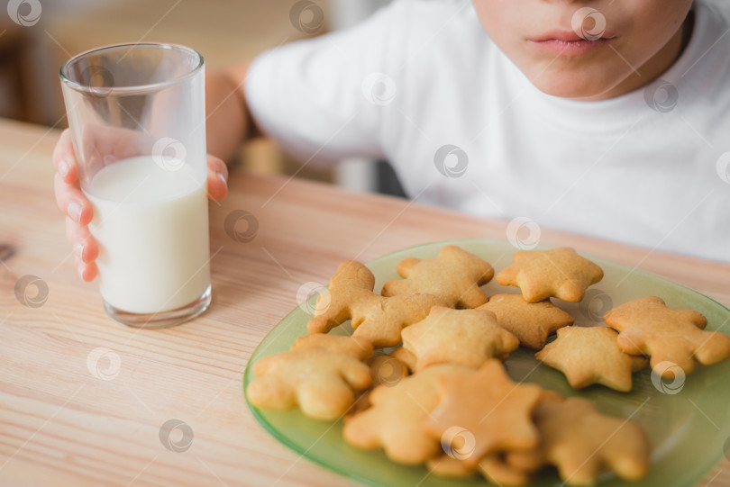 Скачать Домашняя кухня. Крупным планом тарелка с печеньем и стакан молока в руках ребенка. фотосток Ozero
