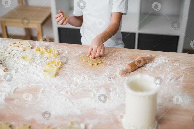 Скачать Крупный план рук ребенка, который готовит печенье дома на кухне. фотосток Ozero