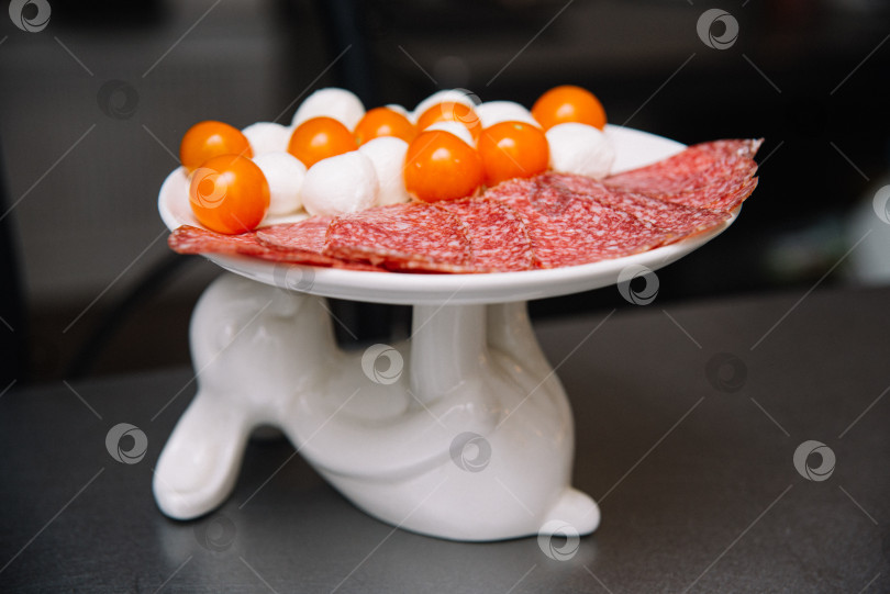 Скачать Блюдо из мясной нарезки с салями, моцареллой и помидорами. фотосток Ozero
