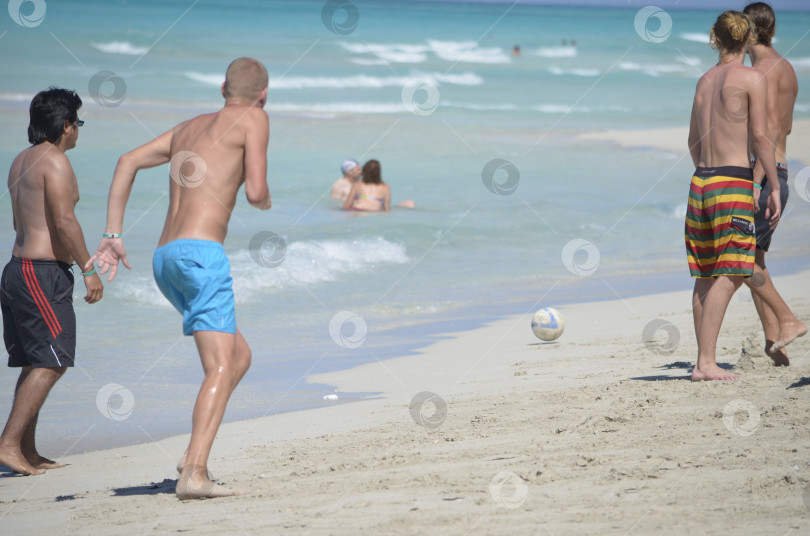 Скачать Молодые люди играют в футбол на пляже Варадеро Мужчины занимаются спортом на песке у моря фотосток Ozero