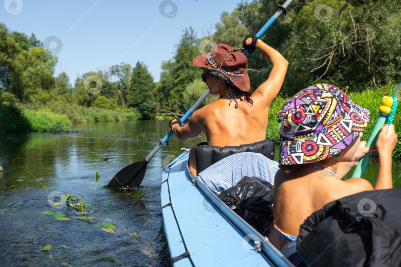 Скачать Семейная прогулка на байдарке. Мама и дочь на лодке по реке, водный поход, летнее приключение. Экологичный и экстремальный туризм, активный и здоровый образ жизни фотосток Ozero