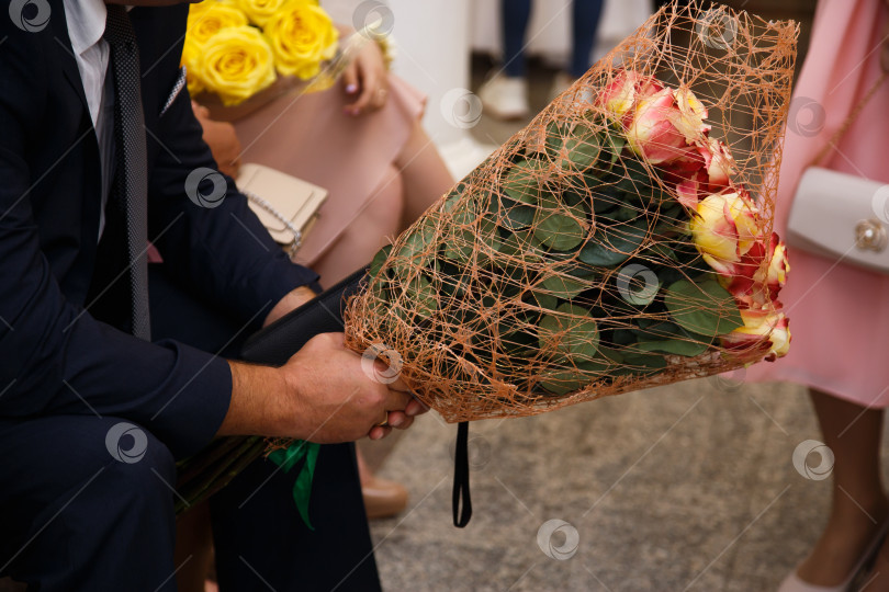 Скачать Крупный план красивого молодого человека в костюме с букетом цветов в руках фотосток Ozero