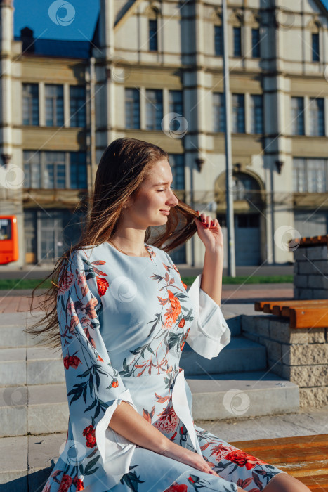 Скачать Стройная молодая девушка стоит на белой набережной. вечер, она выглядит и чувствует себя хорошо. фотосток Ozero